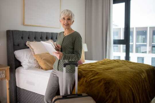 senior woman in bedroom with suitcase
